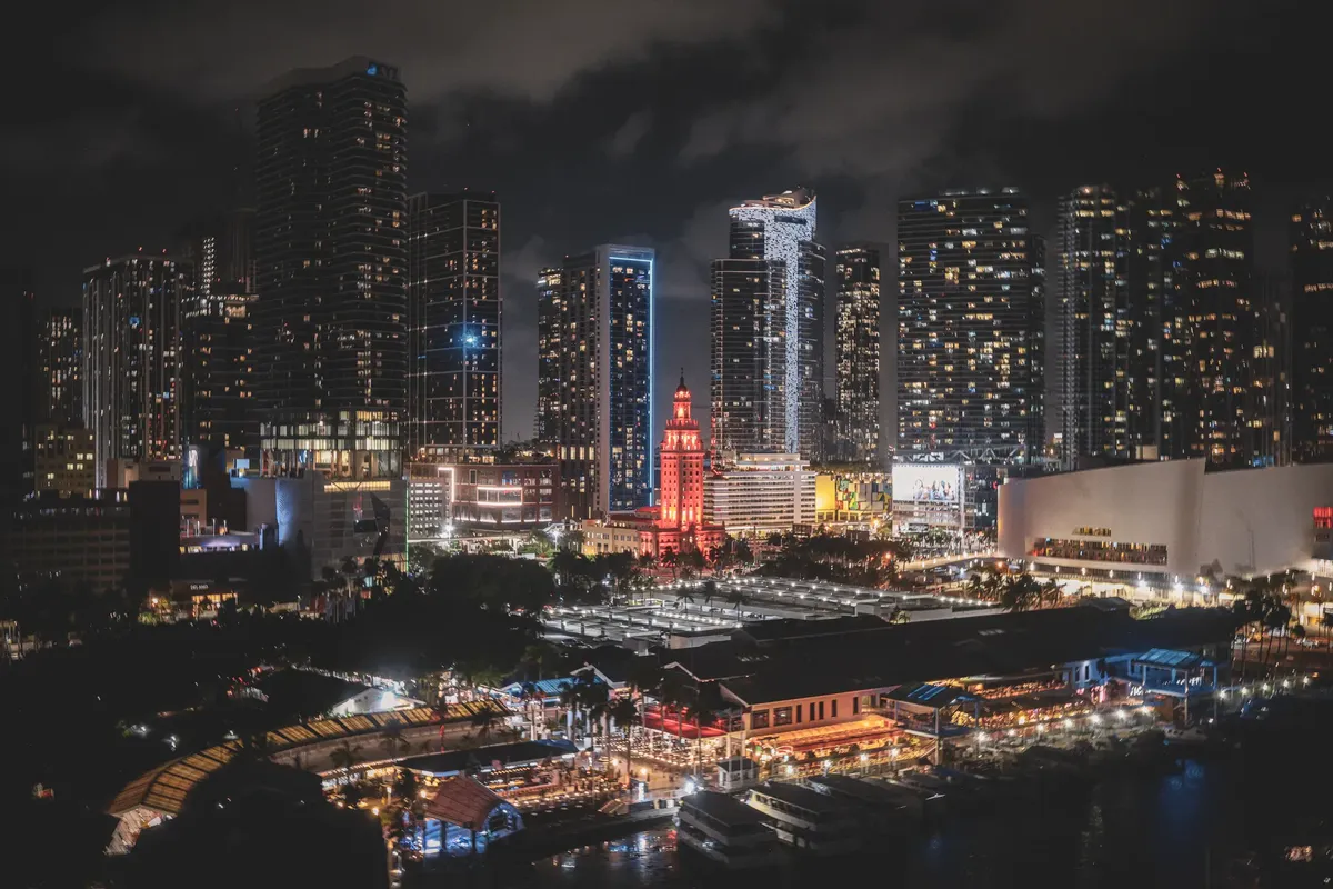 Vibrant Miami downtown skyline at night with illuminated skyscrapers and busy city vibes.